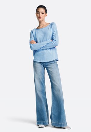 Light blue long-sleeve top with a wide neckline, paired with light blue flared jeans, featuring a soft texture and relaxed fit.
