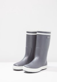 Bottes de pluie en caoutchouc grises avec une finition mate, accents blancs au sommet et à la semelle, et semelle extérieure texturée noire pour une meilleure adhérence.