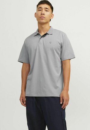 Ljusgrå polo skjorta med korta ärmar, nedvikt krage och en subtil logotyp på vänster bröst. Slätt tyg, avslappnad passform, minimalistisk design.