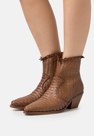 Bottines en cuir tressé marron avec un bout pointu, un bord supérieur effiloché et un petit talon en bois. Surface texturée avec des motifs distinctifs.