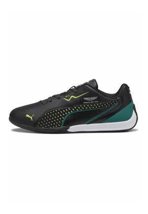 Chaussure de sport basse noire avec des touches vertes, logo Puma, marquage de l'équipe Aston Martin de Formule 1, et semelle blanche.