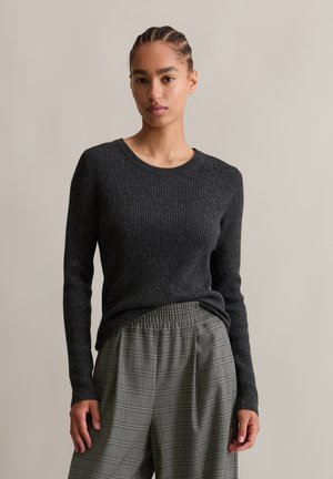 Donkergrijze geribbelde lange mouwen trui met een ronde halslijn, gecombineerd met lichtgrijze geruite wijde broek met elastische tailleband.