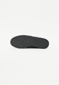 Fekete gumi sneaker talp, amely texturált felülettel és vízszintes barázdákkal rendelkezik. Egyöntetű fekete szín, sima felső résszel.