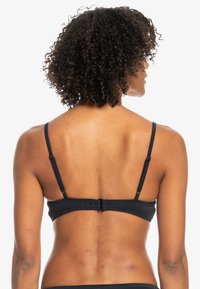 Black ribbed bikini top with adjustable straps, back closure, and a smooth texture, featuring a simple design without additional embellishments.