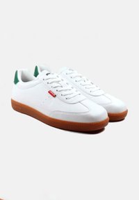 Sneakers bianchi in pelle con punta arrotondata, linguetta verde sul tallone e suola in gomma marrone. Presentano dettagli testurizzati e lacci piatti.