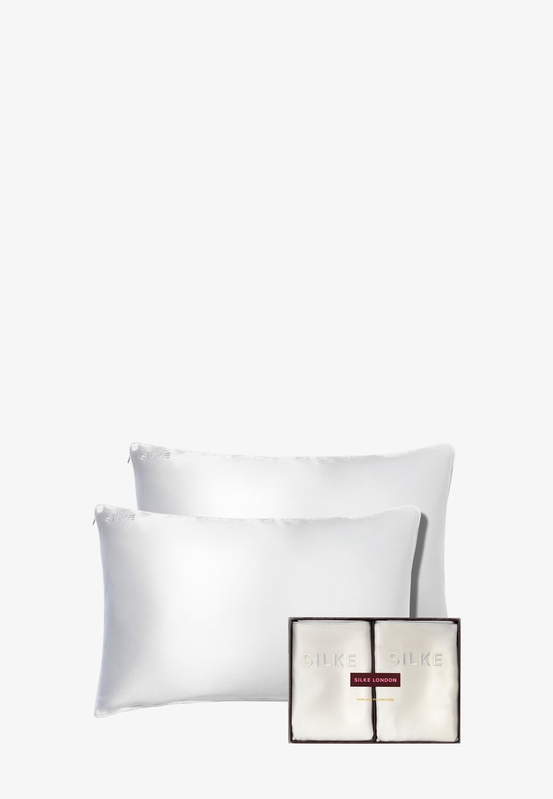 Dos fundas de almohada de seda blanca exhibidas en una caja rectangular. La caja presenta el nombre de la marca en relieve "SILKE LONDON" con detalles en plata y rojo.