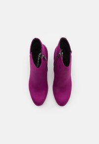 Paire de bottines en daim violet avec fermetures éclair latérales, vues de dessus sur fond blanc.