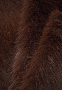 Brown faux fur fabric featuring varying lengths and textures, with soft, glossy strands creating a rich, layered appearance.