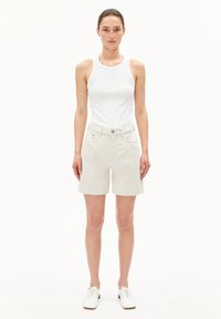 Lichtbeige corduroy shorts met een relaxte pasvorm, voorzien van zijzakken, een knoopsluiting en een platte tailleband. Gecombineerd met een witte tanktop.