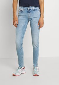 Jeans skinny azul claro de mezclilla, con una cintura de altura media, un sutil desgastado y un clásico diseño de cinco bolsillos.