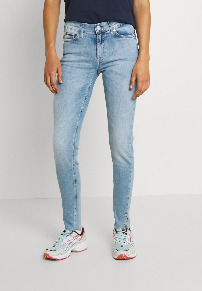 Jeans skinny azul claro de mezclilla, con una cintura de altura media, un sutil desgastado y un clásico diseño de cinco bolsillos.