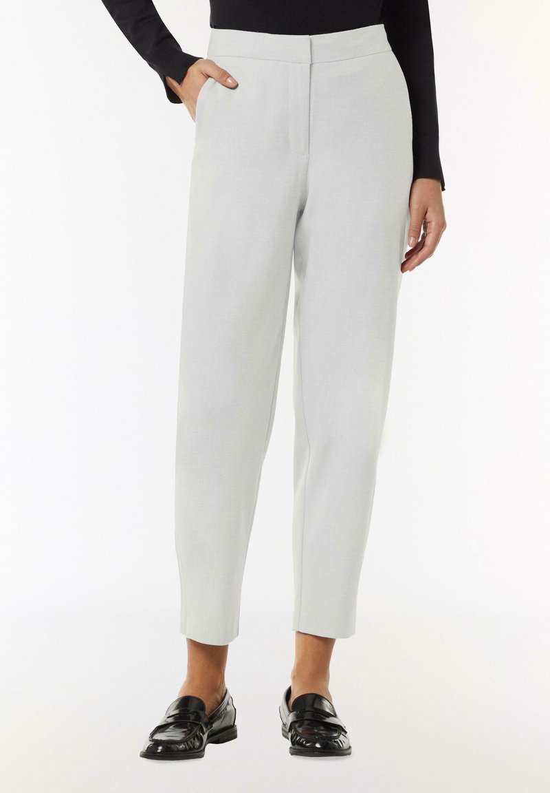 Pantalon tailleur gris clair avec une coupe droite, texture lisse, poches latérales et taille mi-haute, associé à des mocassins noirs.