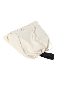 Világos bézs színű anyagból készült húzózsinóros táska fekete pánttal. Egyszerű, strukturálatlan forma, összegyűjtött záródással és minimális márkajelzéssel.