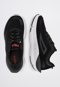 Sneakers atletici neri con tomaia in rete, suola bianca e sottili dettagli rossi. Presentano un design con lacci e un colletto imbottito per il comfort.
