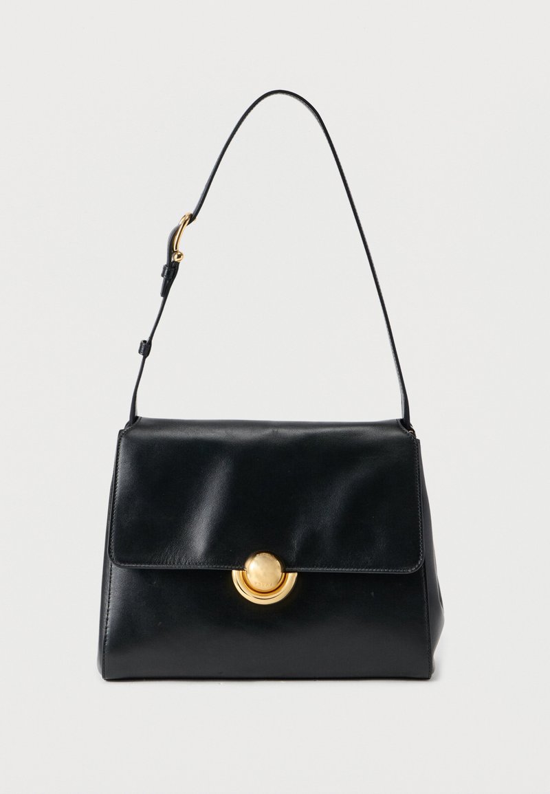 Sort læderhåndtaske med struktureret design, magnetlukning og en guldfarvet cirkulær detalje. Justerbar skulderrem medfølger.