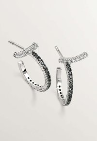 Pendientes de aro de plata con diseño curvado, piedras negras incrustadas a lo largo del borde y una superficie texturizada con acentos claros en la parte superior.