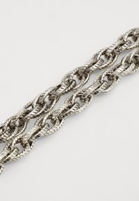 Silver metal chain featuring intertwined links, textured surface with diagonal grooves, and smooth edges, arranged in a continuous pattern.