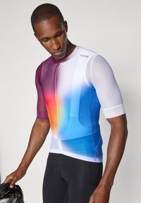 Maillot de vélo à manches courtes en dégradé de couleurs allant du violet au bleu, fabriqué en tissu en maille, avec une fermeture éclair devant et des accents blancs.