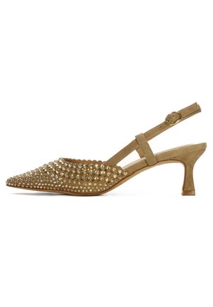 Zapato tipo slingback beige con punta afilada, adornado con tachuelas doradas, parte superior de ante texturizado y un tacón bajo y moderado. Destacado con una correa de hebilla.