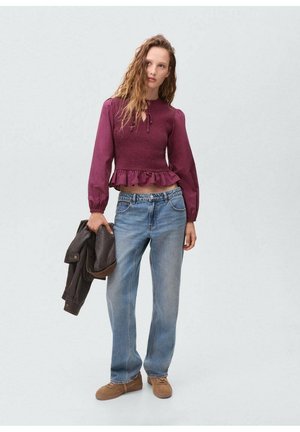 Maroon peplum top with smocking and ruffled hem, paired with light blue straight-leg jeans and brown slip-on shoes. Holding a dark jacket.