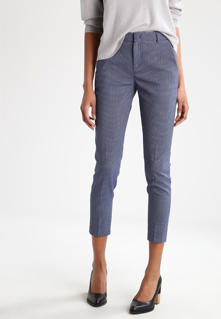 Navy patterned trousers with a slim fit, cropped length, and subtle texture. Paired with black high-heeled shoes.