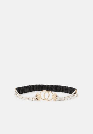 Ceinture élastique noire à la taille avec détails en perles et perles dorées et une boucle double anneau dorée au centre.