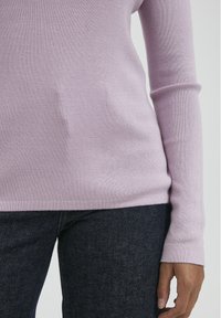 Pulover tricotat de culoare mov deschis, cu mâneci lungi, textură fină și design ajustat, asortat cu blugi din denim închis.