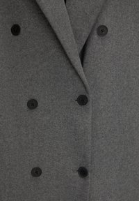 Grå dobbeltbrystet frakke lavet af tekstureret uldstof, med sorte knapper og en notch lapel-design.