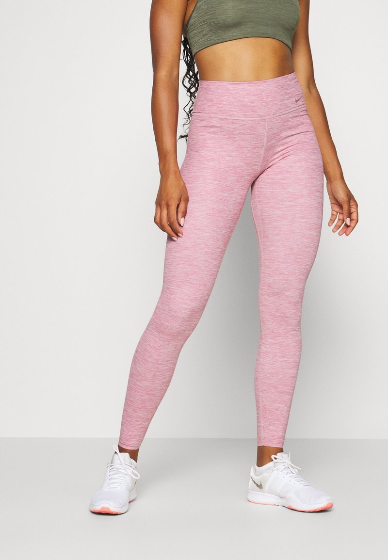 Leggings rosa melangiati con vita alta, realizzati in materiale elastico; abbinati a scarpe da ginnastica bianche con accenti chiari.