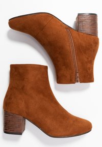 Bruine suède enkellaarsjes met een puntige neus, een zijrits en een gestapelde houten hak. Gladde textuur met een effen kleurafwerking.