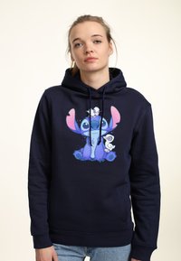 Felpa blu navy con una grafica di un personaggio dei cartoni animati, caratterizzata da espressioni facciali dettagliate e accenti nei colori pastello. Tessuto misto cotone.