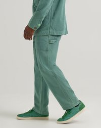 Light green corduroy jacket and pants with a ribbed texture, paired with green sneakers featuring a textured accent.