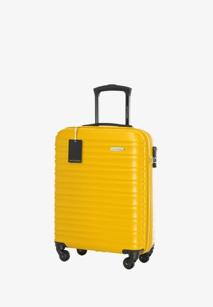 Gelber Hartschalenkoffer mit vertikalen Rillen, schwarzem ausziehbarem Griff, vier Rädern und einem abnehmbaren Anhänger mit der Aufschrift "WITTCHEN."