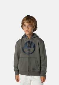 Grauer Reißverschluss-Hoodie aus Baumwollmaterial, mit einem großen navyfarbenen Logo auf der Brust und einem Textdetail am Saum. Mit Seitentaschen.