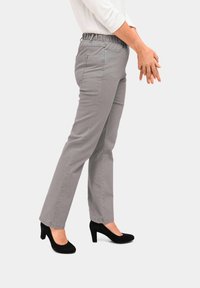 Graue, figurbetonte Hose mit elastischem Bund, geradem Beinansatz und subtiler Textur, kombiniert mit schwarzen High-Heels.