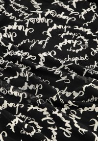 Zwarte stof met witte cursieve tekst "chapest" die herhaaldelijk in cirkelvormige patronen over het oppervlak is verspreid.