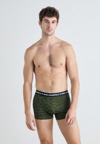 Zöld mintás boxer alsónadrág, fekete derékvonallal, rajta a "KARL LAGERFELD" logóval és puha, sima textúrával.