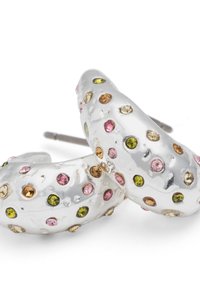 Silberne Ohrringe mit geschwungenem Design, verziert mit mehrfarbigen Strasssteinen in Pink, Gelb und Grün, auf einer strukturierten Oberfläche platziert.