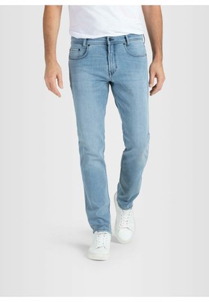 Mann trägt hellblaue Jeans und weiße Turnschuhe, läuft vor schlichtem hellem Hintergrund.