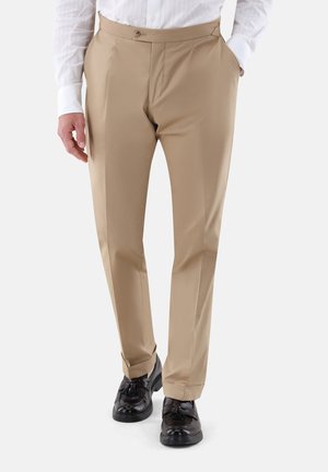 Beige maßgeschneiderte Hose mit tailliertem Schnitt, flacher Front und Taschen. Tragen mit einem weißen gestreiften Hemd und schwarzen Dressschuhen.