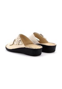 Sandali in pelle beige con motivo floreale ritagliato, dettagli testurizzati e suola in gomma nera. Tacco aperto con soletta imbottita.