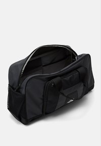 Black duffel bag made of durable fabric; features mesh side pockets, dual handles, and a spacious interior with a zippered opening.