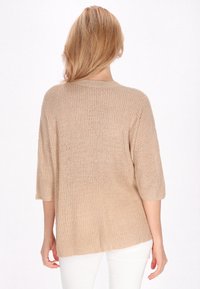 Beige gestrickter Pullover mit lockerer Passform, kurzen Ärmeln und rundem Ausschnitt. Der strukturierte Stoff zeigt ein feines Strickmuster.