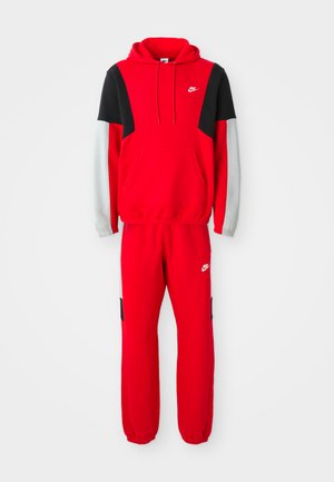 Roter Nike-Hoodie und passende Jogginghose mit schwarzen und grauen Akzenten, versehen mit weißen Nike-Logos auf der Brust und dem linken Oberschenkel.