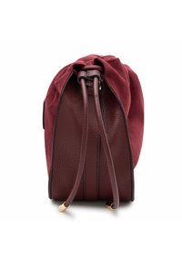 Borsa rotonda bordeaux che combina suede morbido e pelle granata. Presenta una chiusura con coulisse, dettagli laterali e una superficie testurizzata.