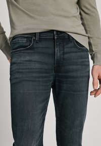 Mörkgrå denimjeans med slim fit, subtil blekning, femfickdesign och ett robust midjeband med knappstängning.