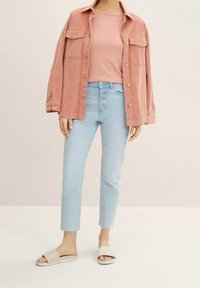 Světle růžová kordurová košile-jacket, růžové tričko, světle modré zkrácené džíny s roztrhaným lemem a béžové prošívané klouzačky.