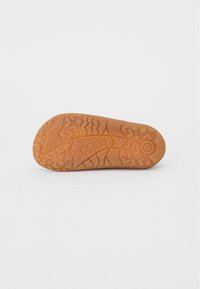 Rubber shoe sole with a textured pattern, featuring zigzag and traction designs in orange-brown. Includes logo imprint and size detail.