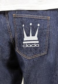 Dark blue denim jeans with a back pocket featuring a white crown logo and the text "dada" in a stylized font.