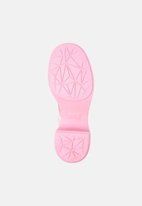 Podešev boty z růžového gumového materiálu, se geometrickým vzorem a texturovanými úchyty, navržená pro trakci a odolnost.